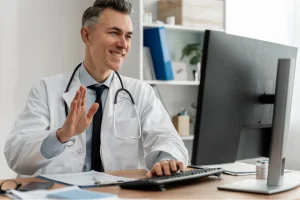 Doctor conducting a virtual consultation while reviewing Telehealth CPT Codes on a computer for accurate medical billing.