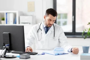 Doctor reviewing patient billing documents and claims related to CO-50 denial code description in a clinical office.
