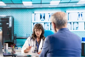 Patient Identifiers for HIPAA compliance discussed by doctor reviewing patient records with individual in clinic