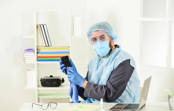 Healthcare professional in protective gear using device for anesthesia billing and medical documentation